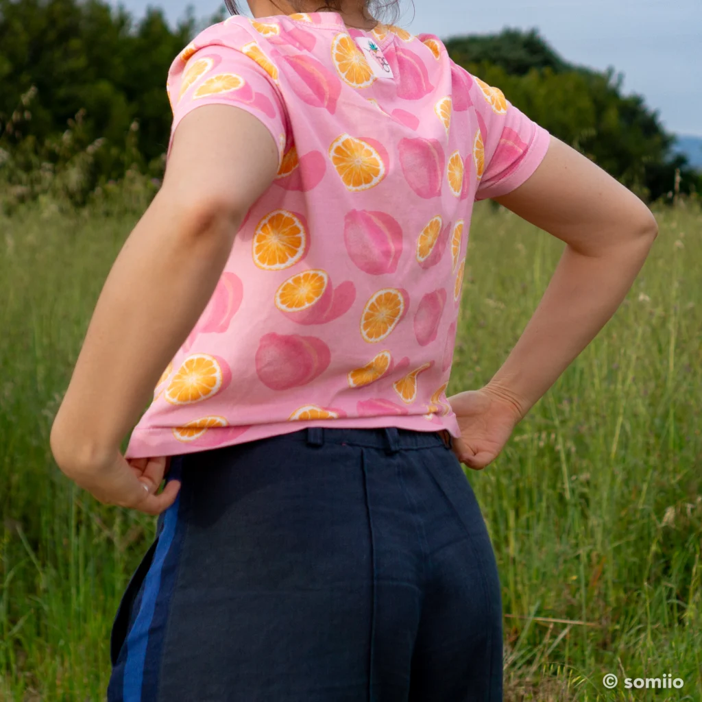 Pantalon Twig Woven Pant vu de dos, plis nervures et fond ample en lin bleu marine, dans un champ de fleurs sauvages