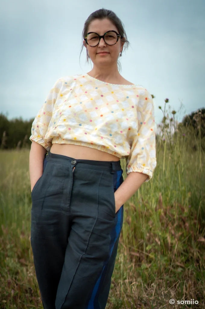 Forme barrel du pantalon Twig Woven Pant en lin marine, vue de face jambe tendue, avec un t-shirt rose imprimé agrumes